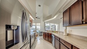 A modern kitchen with stainless steel appliances, wooden cabinets, and a large window offering a view of the outdoors.