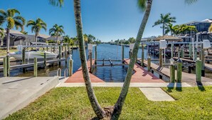 A marina with docked boats, palm trees, and a waterway.