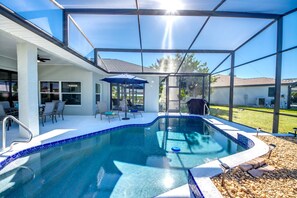 Ein Schwimmbecken mit Glasüberdachung, Terrassenmöbeln und freiem Blick auf die Umgebung.