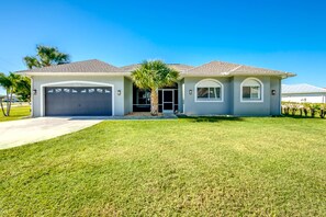 Einbungalow mit Garage, Rasen und einer Palme.