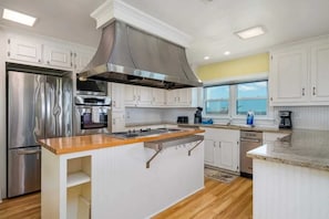 A modern kitchen with stainless steel appliances, a central island, and white cabinetry.