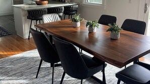 Een moderne keuken met witte kasten, een houten eiland en een eethoek met een houten tafel en zwarte stoelen.