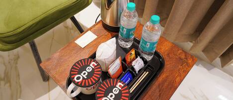 A tray with two mugs labeled "Open," a kettle, bottled water, and a tissue box.