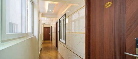 A hallway with a wooden door marked "202", a marble wall, and a tiled floor.