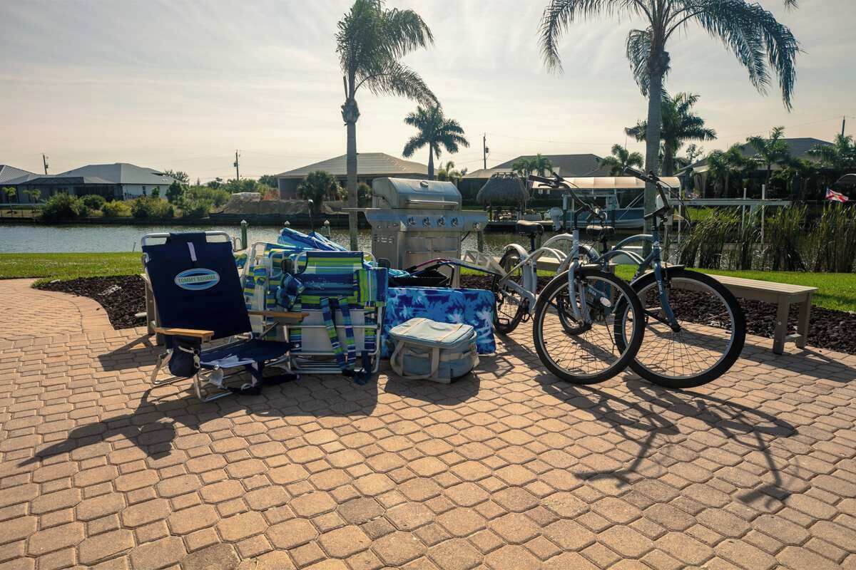 Un espacio pavimentado con una parrilla, bicicletas y una silla con una toalla.