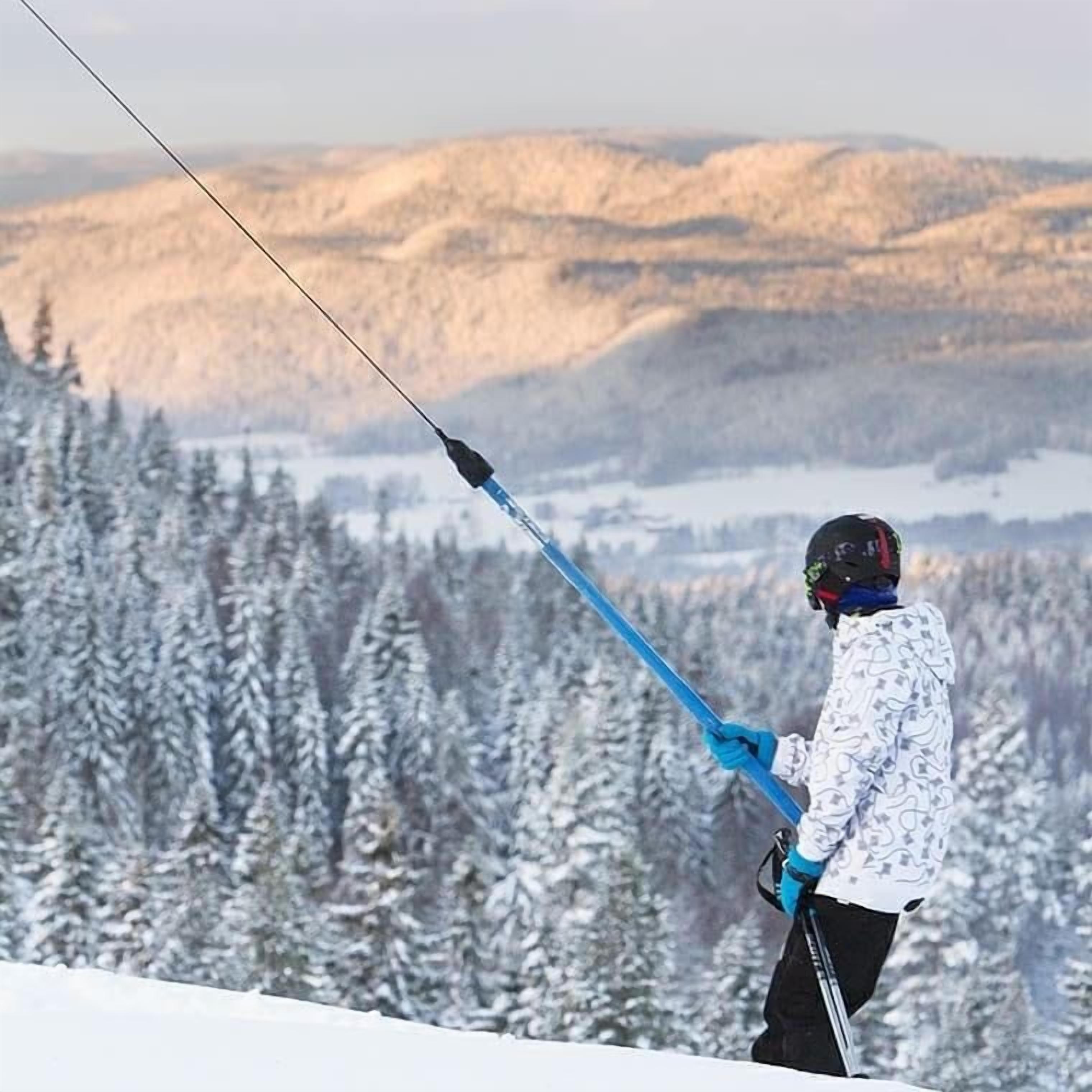 En person står på ski i et sneklædt terræn med udsigt til snebeklædte træer og fjerne bjerge.
