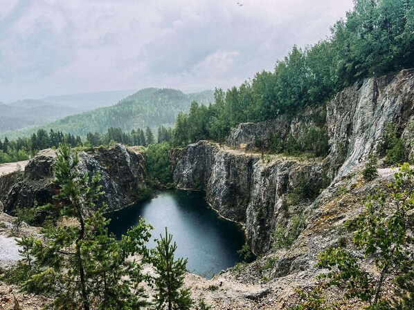 A natural landscape with a rocky terrain, a small body of water, and dense forest.