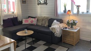 A cozy living room with a dark grey sofa, a small round table with a glass, and a checkered rug.