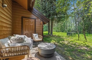 A wooden cabin with a porch, a bed, two chairs, and a round table. - Cozy & Modern family friendly McCall Retreat – Walk to Lake Payette and Downtown (McCall)