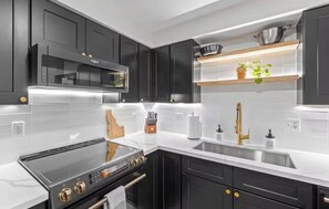 A modern kitchen with black cabinets, a stainless steel sink, and a built-in microwave. - Cozy & Modern family friendly McCall Retreat – Walk to Lake Payette and Downtown (McCall)