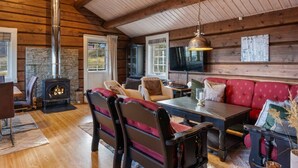 A log cabin interior with a stone fireplace, wooden furniture, and a television. - Trysilfjell 615 by Vacation Trysil (Trysil)