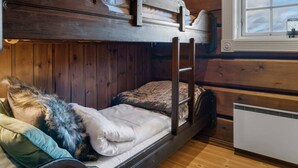 A bunk bed with a wooden headboard, a window with a view, and a small kitchenette area. - Trysilfjell 615 by Vacation Trysil (Trysil)