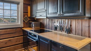 A kitchen with wooden paneling, a microwave, a toaster, and knives hanging on the wall. - Trysilfjell 615 by Vacation Trysil (Trysil)