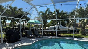 A swimming pool with a covered area, lounge chairs, and a grill. - 3/2 Luxury Waterfront Pool Home (Punta Gorda)