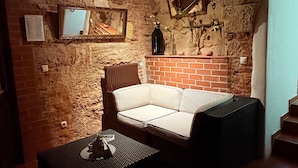Ein gemütliches Zimmer mit Kamin aus Backstein, einem weißen Sofa, einem kleinen Tisch und einer Wand aus Stein.