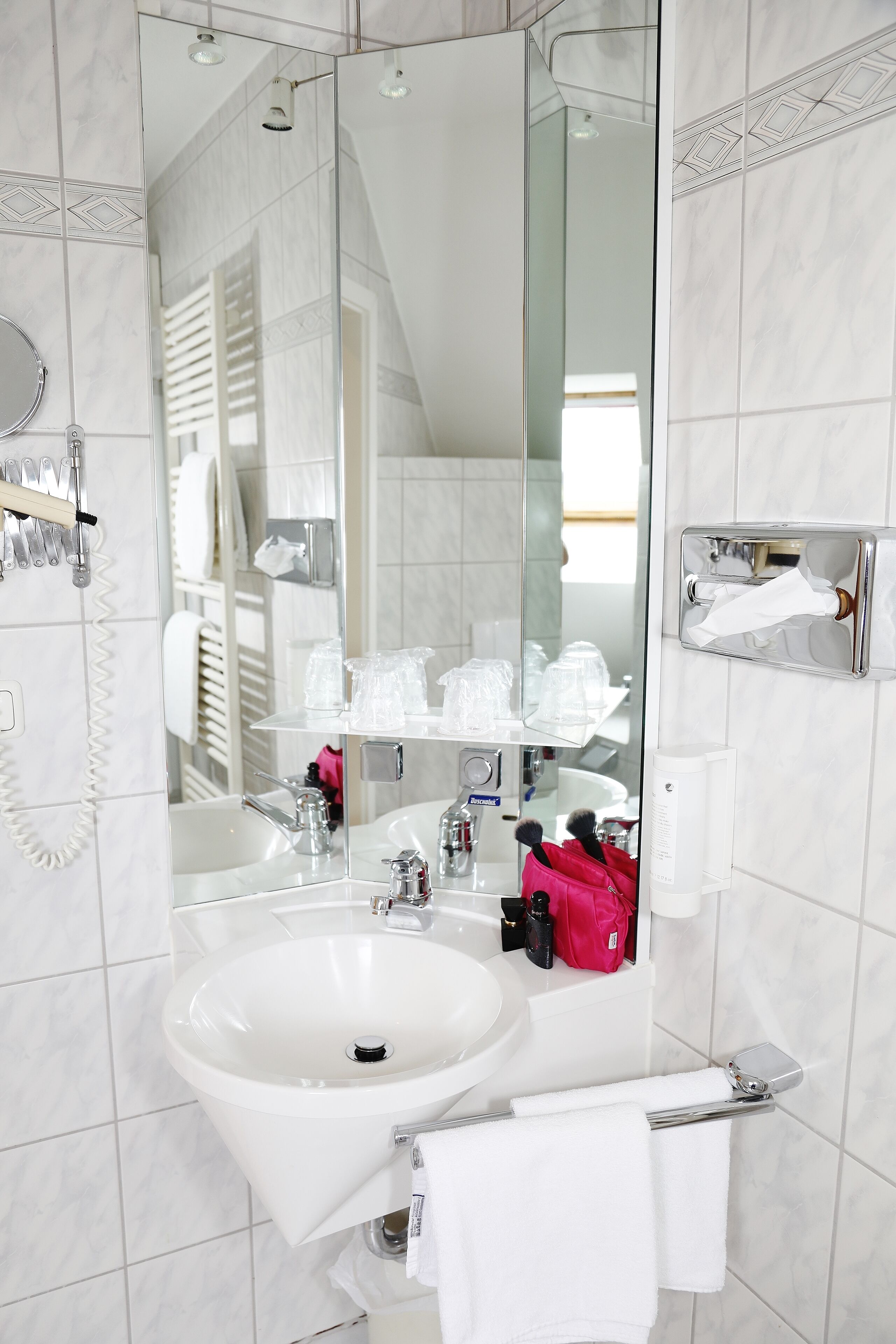 A modern bathroom with a large mirror, a sink, and a glass shower enclosure.