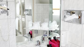 A modern bathroom with a large mirror, a sink, and a glass shower enclosure.