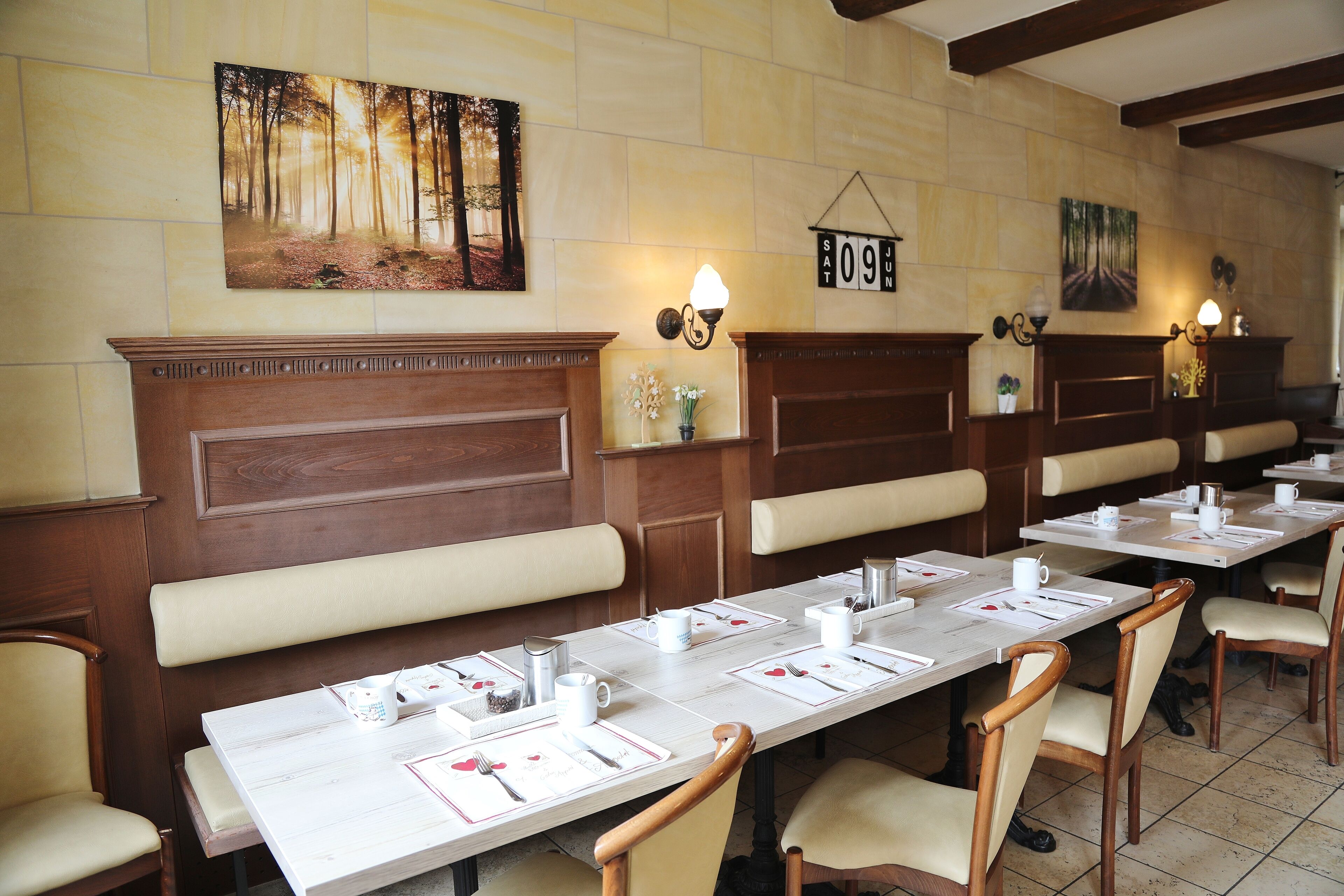 A restaurant with long tables, wooden booths, and wall-mounted artwork.