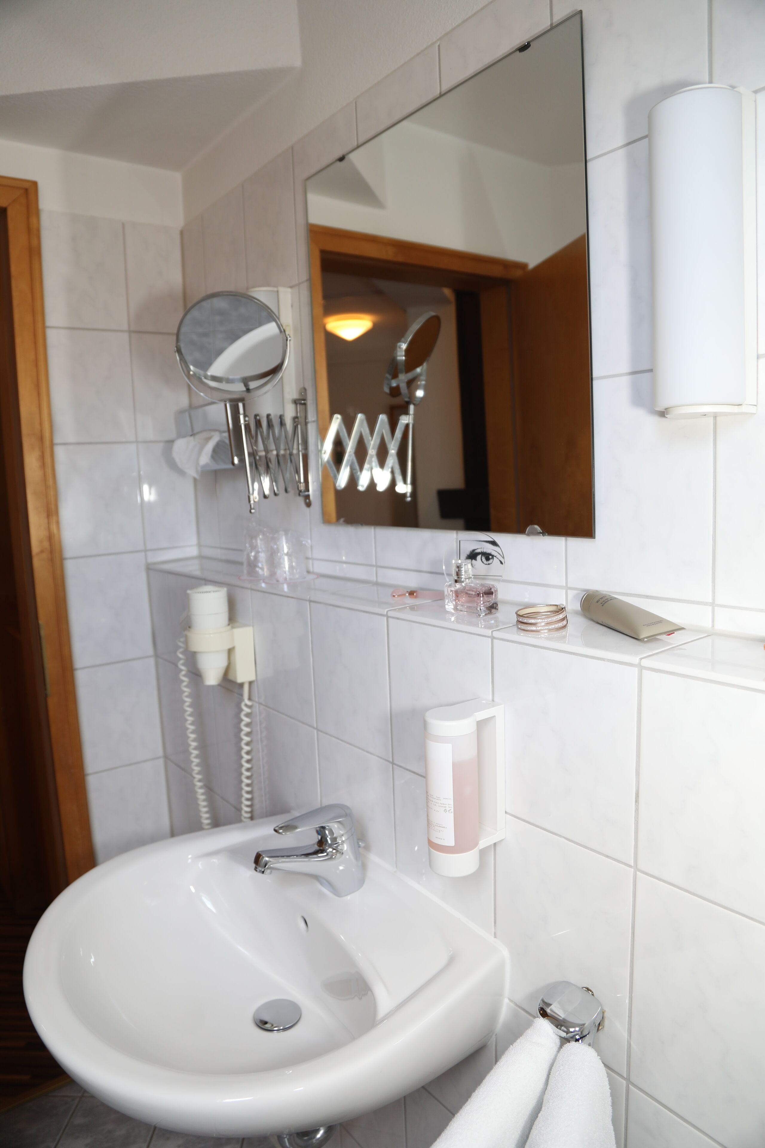 Une salle de bain avec un lavabo blanc, un miroir et un porte-serviettes.