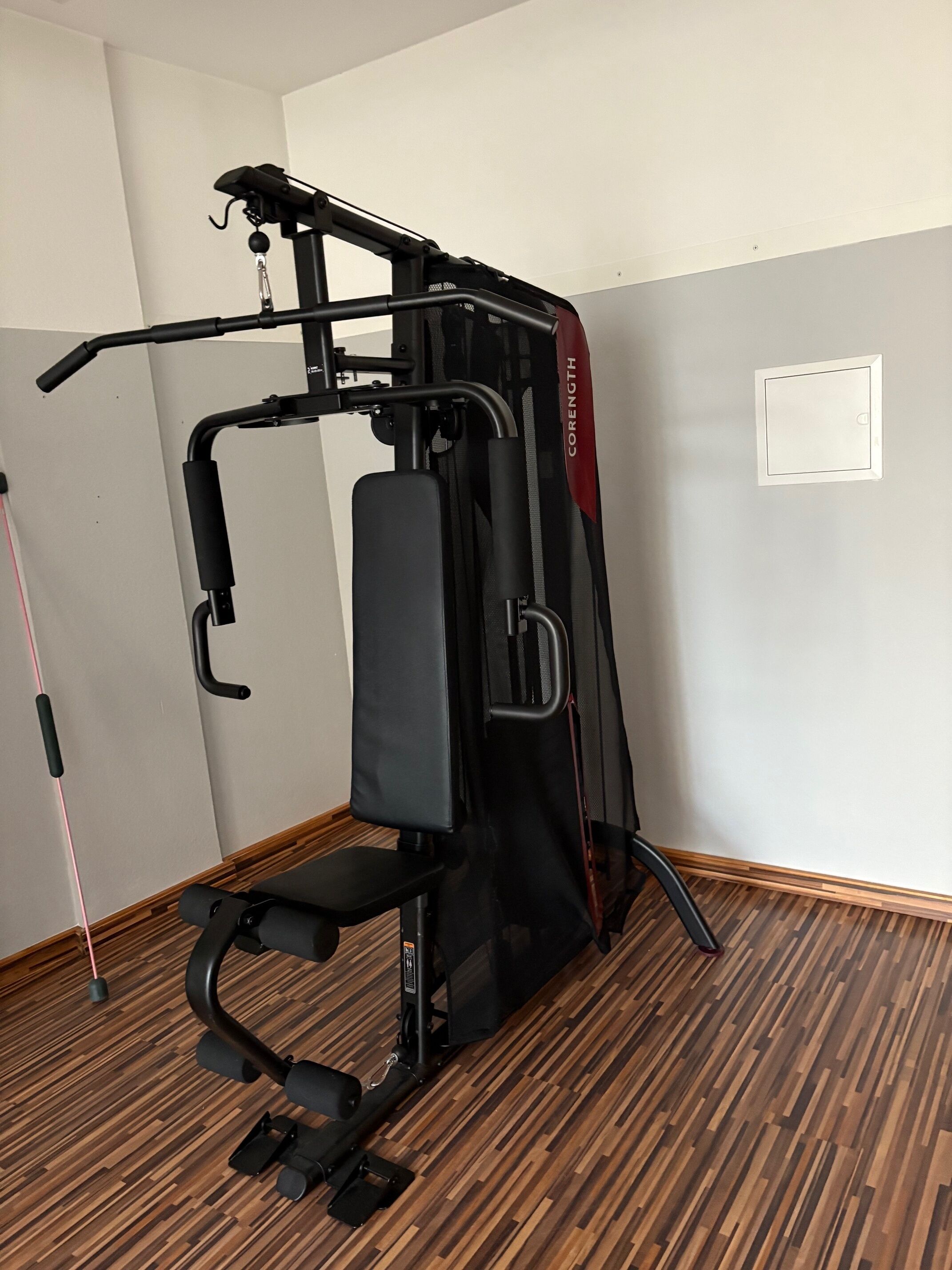Gimnasio en casa equipado con barra de dominadas, banca para pesas y máquina de poleas.
