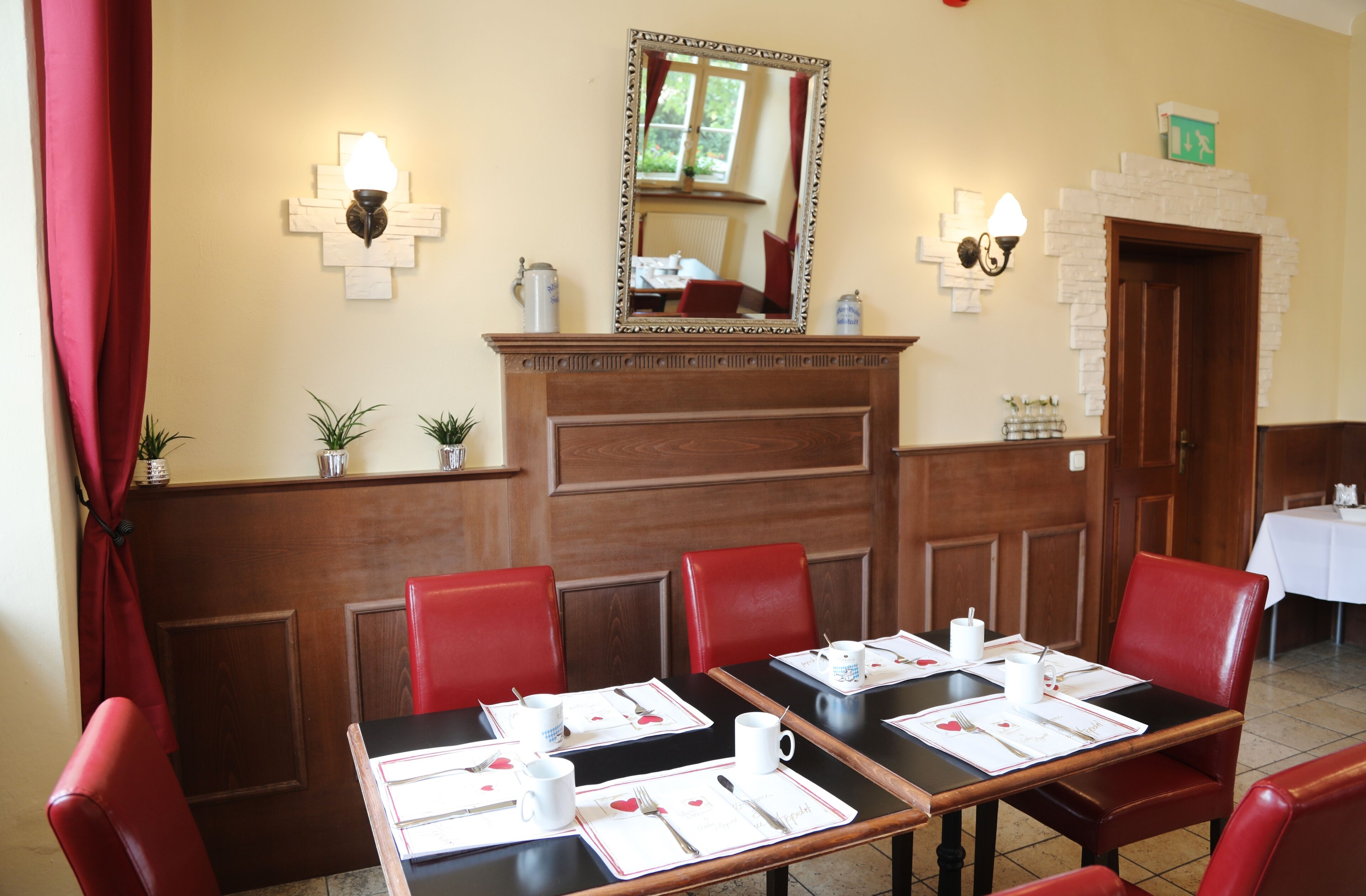 Zona pranzo con sedie rosse, tavoli neri e tovagliette bianche.