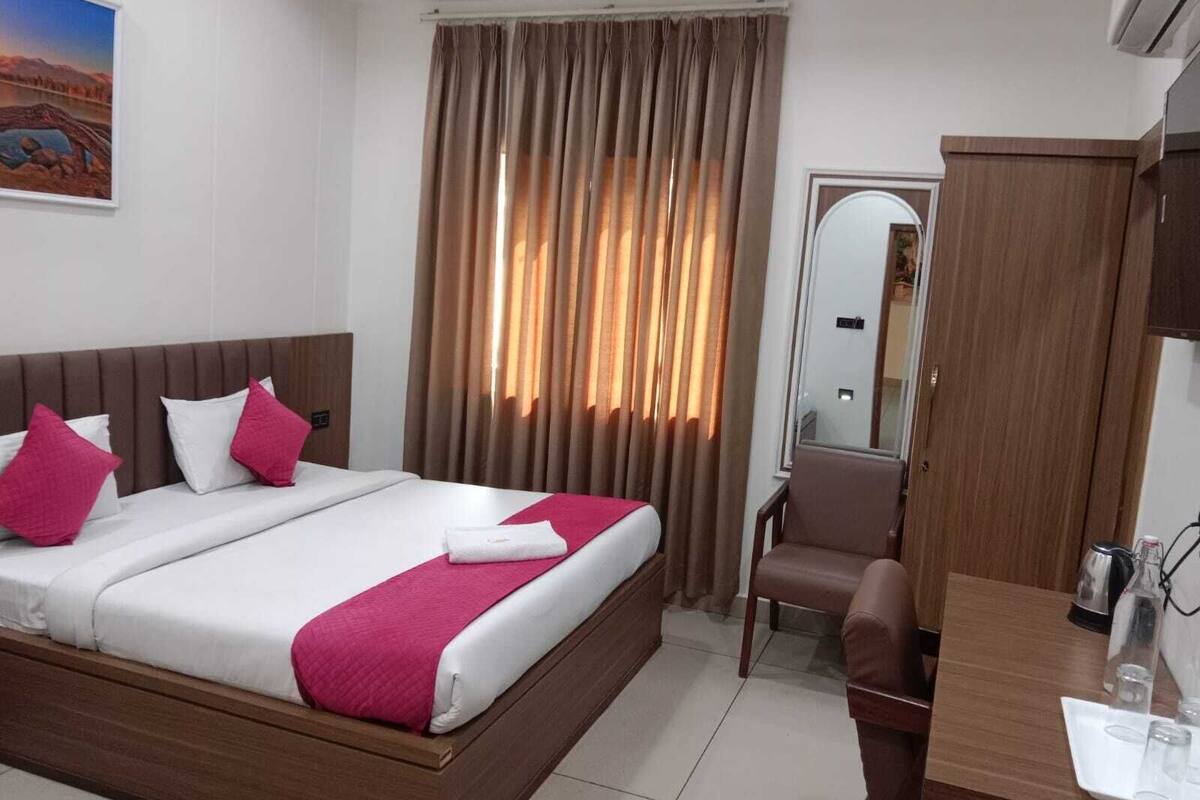 A hotel room with a bed, a desk, a chair, and a window with curtains.