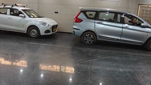 Two cars parked in a well-lit indoor space with a polished floor and ceiling fans. - Gokul Dham Haridwar (Haridwar)