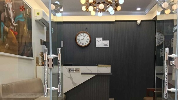 A reception area with a reception desk, a clock, a sofa, and a patterned rug. - Gokul Dham Haridwar (Haridwar)