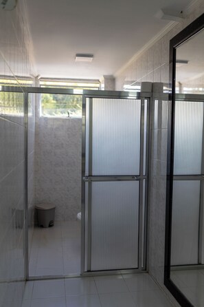 Ein modernes Badezimmer mit Duschkabine aus Glas, weißen Fliesen und einem sichtbaren WC.