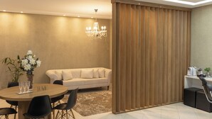 A modern living room with a round wooden table, black chairs, a beige sofa, a chandelier, and a wooden partition. -  JHS Palace Hotel  (Boa Esperança)