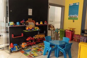 A children's play area with toy cars and trucks, a blue table, and chairs.