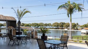 An outdoor patio with tables and chairs, overlooking a body of water and trees. -  JHS Palace Hotel  (Boa Esperança)