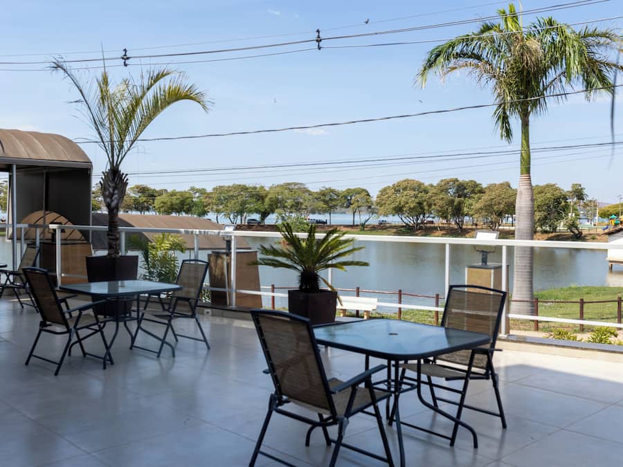 An outdoor patio with tables and chairs, overlooking a body of water and trees.