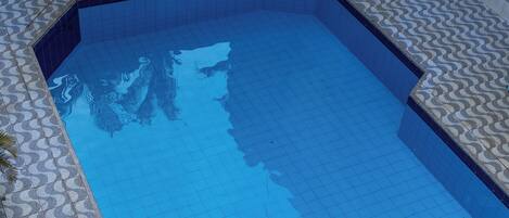 A rectangular swimming pool with a tiled edge and a patterned floor around it.
