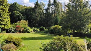 Un jardin luxuriant, avec une grande variété d’arbres et d’arbustes, une pelouse bien entretenue et un ciel dégagé.