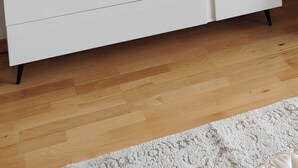 Une commode blanche surmontée d’un miroir rond, un tableau encadré posé sur la commode et un petit plateau sur le dessus.