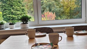 Un coin repas avec une grande fenêtre, une table en bois et plusieurs chaises.