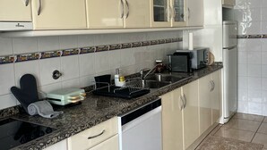 Una cocina con armarios blancos, microondas, tostadora y lavavajillas.