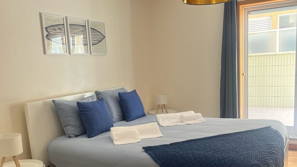 Un dormitorio con cama, mesitas de noche, alfombra y vistas al exterior.