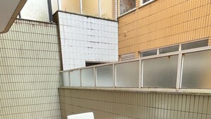 Un patio al aire libre con una mesa de vidrio rodeada de sillas de mimbre con cojines.