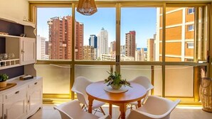 A modern room with a large window, a round dining table, and white chairs. - CHARMING APARTMENT IN THE HEART OF LEVANTE (Benidorm)