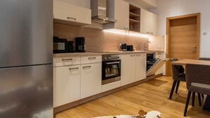 Une cuisine moderne dotée d’appareils électroménagers en acier inoxydable, de meubles en bois et d’un four encastré.