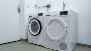 Deux machines à laver à chargement frontal, de couleur blanche, se trouvent dans une pièce dotée d’une porte blanche et d’un plancher de couleur claire.