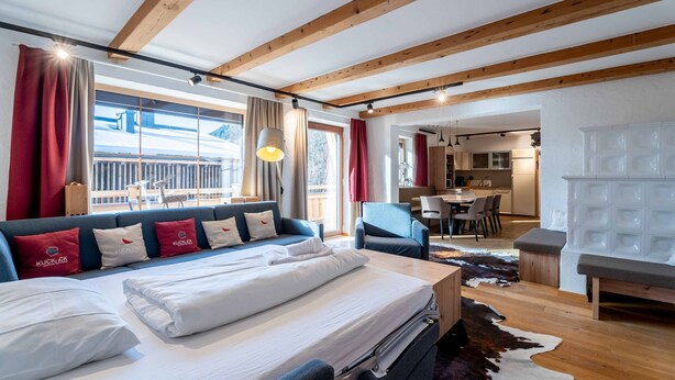 Een hotelkamer met een bed, een bank, een eethoek en een keuken.