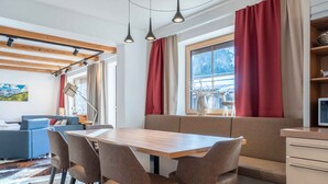 Een moderne eetruimte met een houten tafel en stoelen, een bank en een raam met gordijnen.