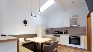 A modern kitchen with a dining area, wooden flooring, and pendant lighting. - KUCKUCK Hinterthal - Top 5 (Maria Alm am Steinernen Meer)