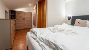 A bedroom with a bed, a wardrobe, and a nightstand. - KUCKUCK Hinterthal - Top 5 (Maria Alm am Steinernen Meer)