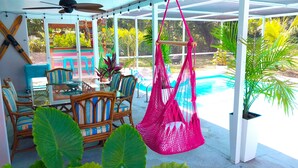 Un patio coperto con piscina, mobili in vimini e amache sospese.