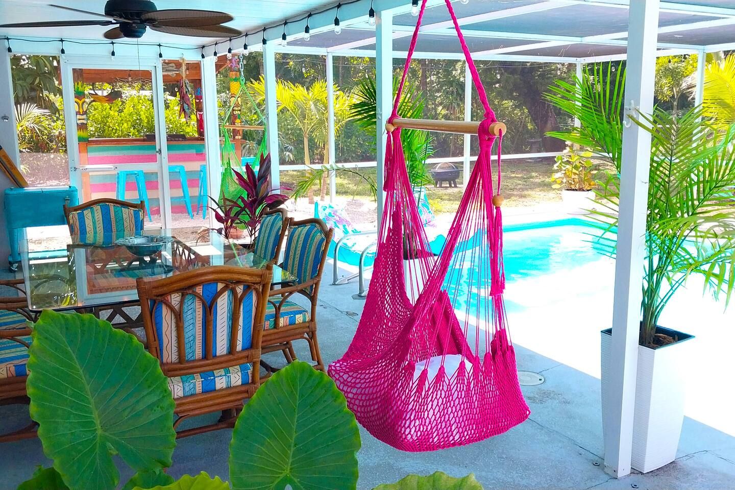 A covered outdoor area with a pool, seating, and hanging hammocks.