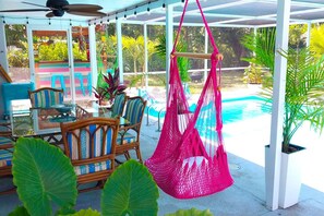 A covered outdoor area with a pool, seating, and hanging hammocks. - Heated Pool / A Tiki Bar / Near The Beach / 2PM Check-in / Kids & Pet fr. (Fort Myers)